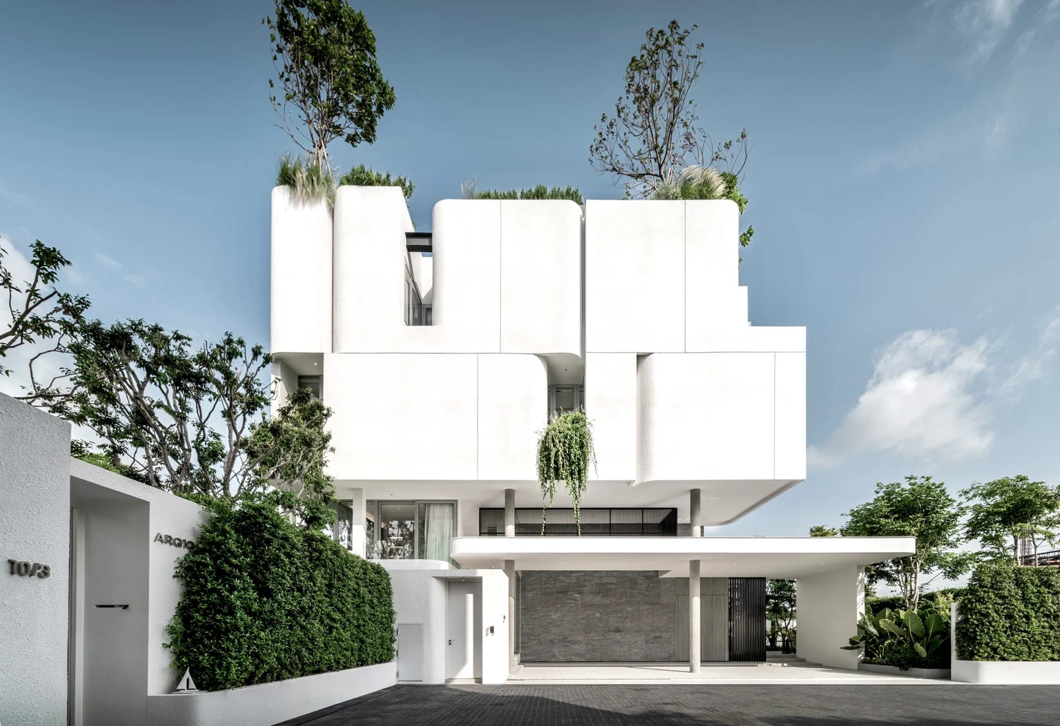 Street-facing view of a white residential building with planted rooftops, from Tom Jakkapat’s development work