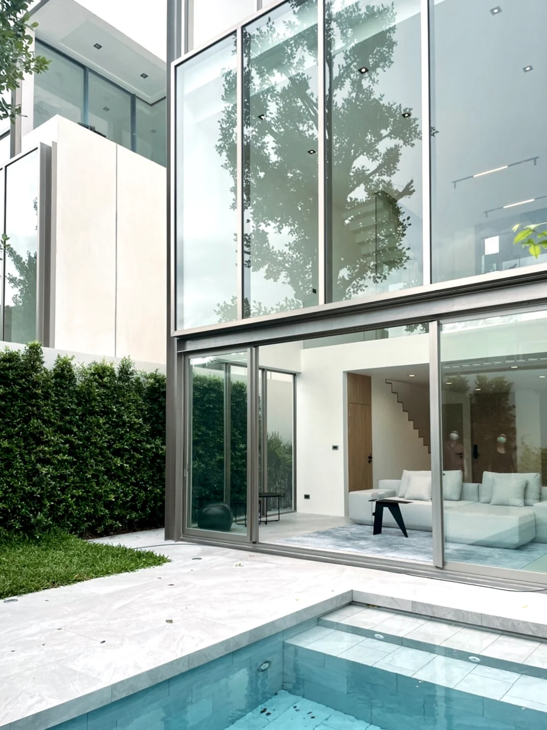 A living room opening onto a courtyard and pool in a project developed by Tom Jakkapat