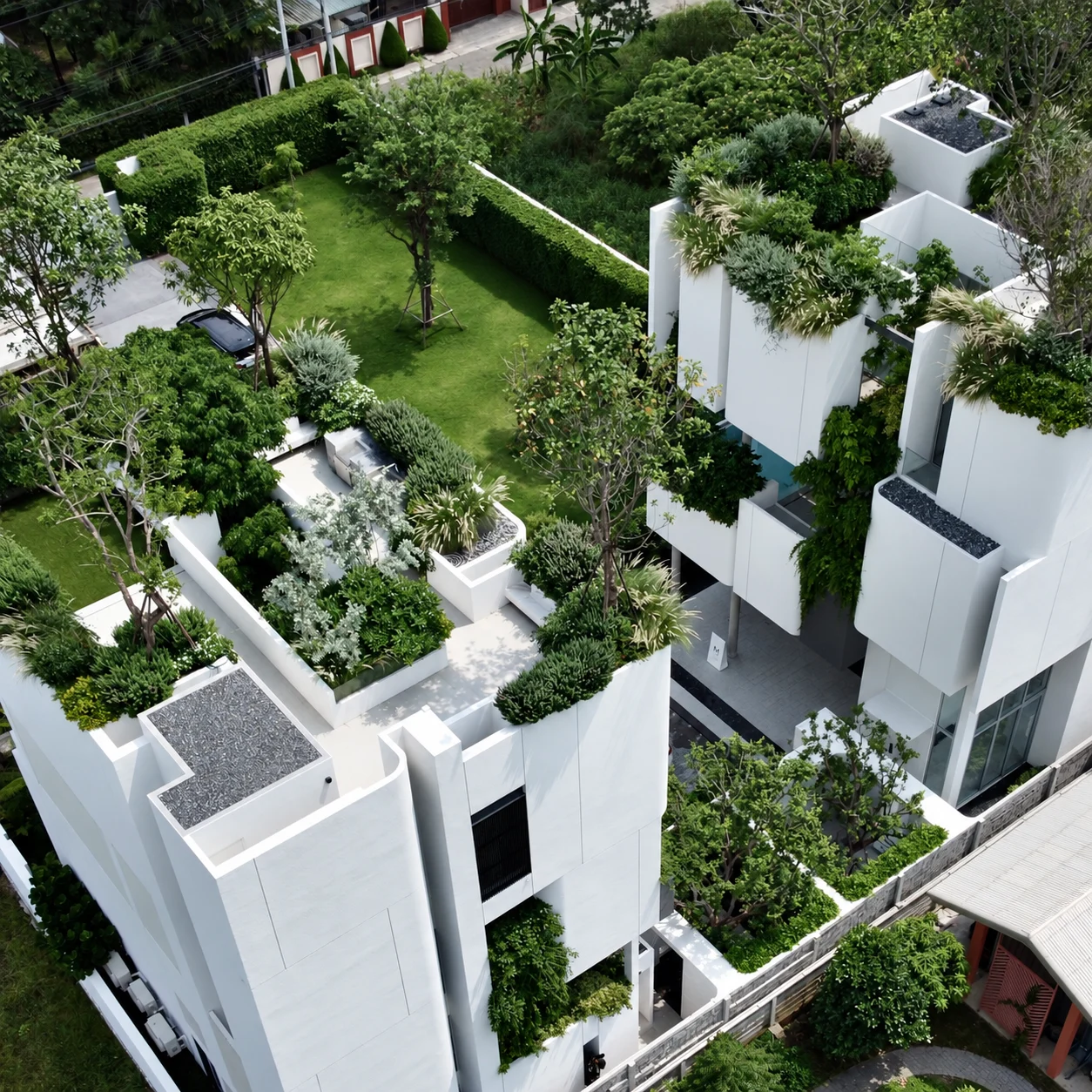 Aerial view of planted rooftop terraces and white building volumes on the same development project